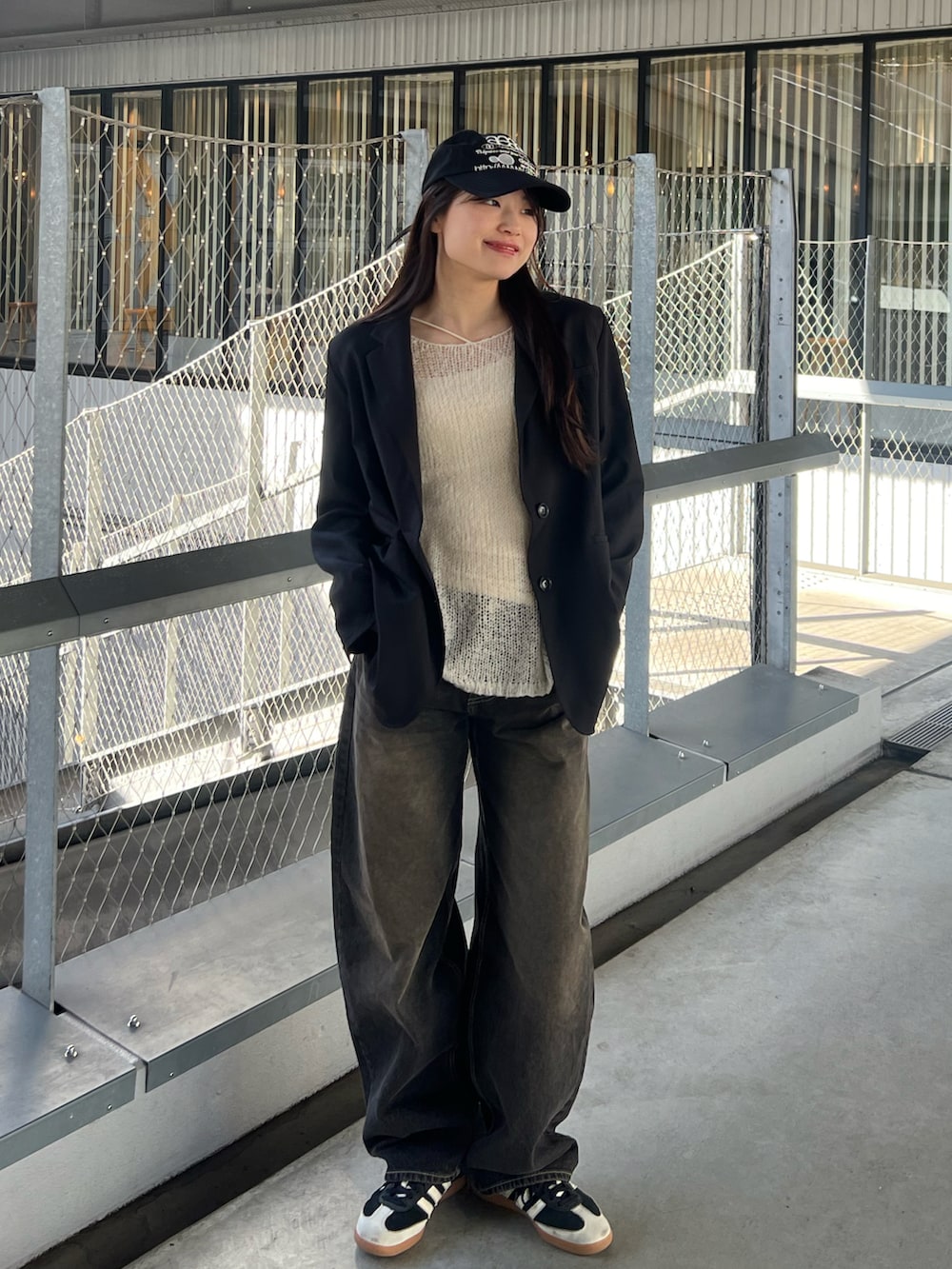 ホワイト系のニット/セーター、ブラック系のテーラードジャケット、ブラック系のデニムパンツを着用したレディースの春コーディネートの3枚目の写真