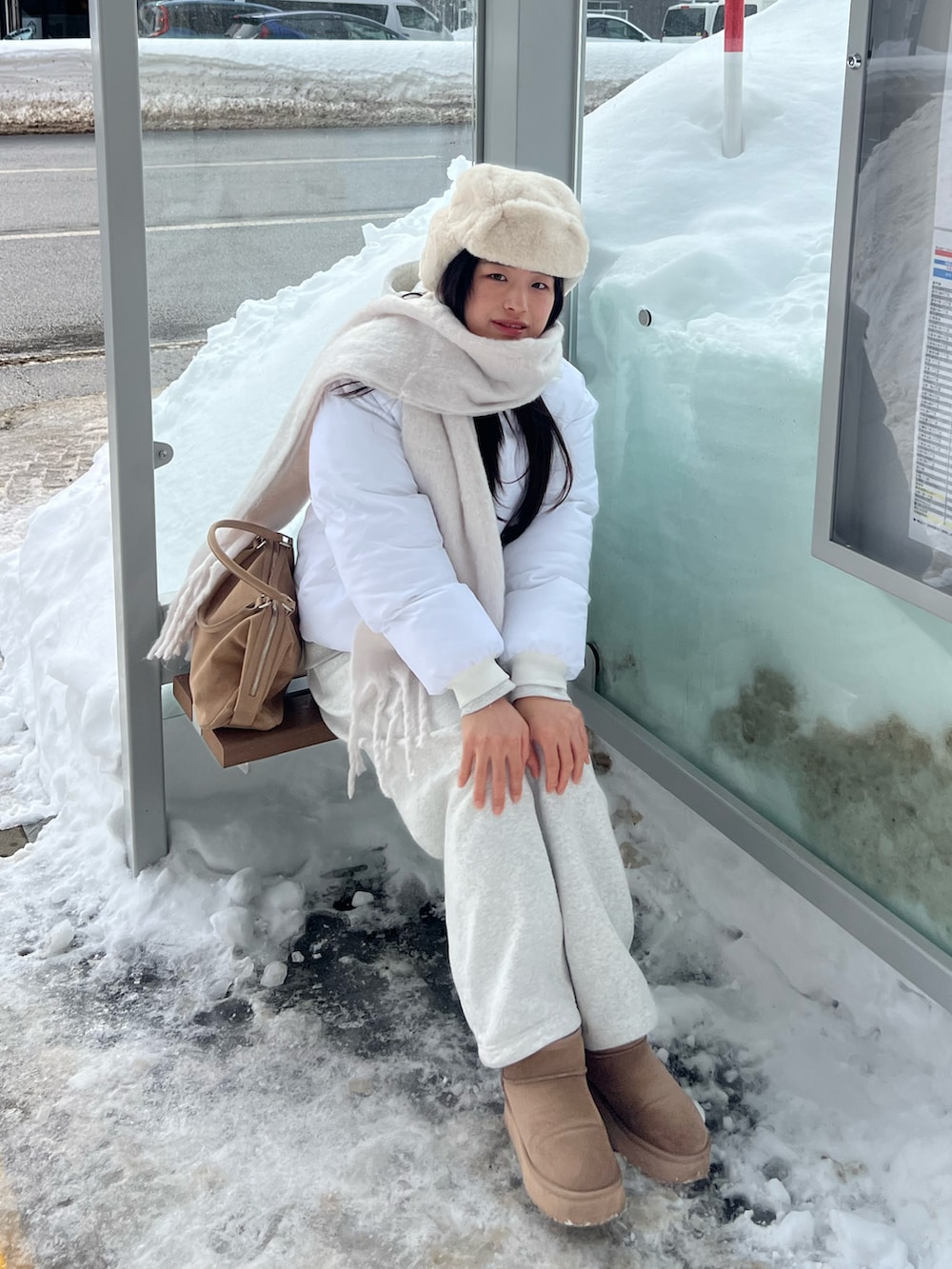 ベージュ系のボストンバッグ、ホワイト系のスウェットパンツ、ホワイト系のマフラーを着用したレディースの春コーディネートの2枚目の写真