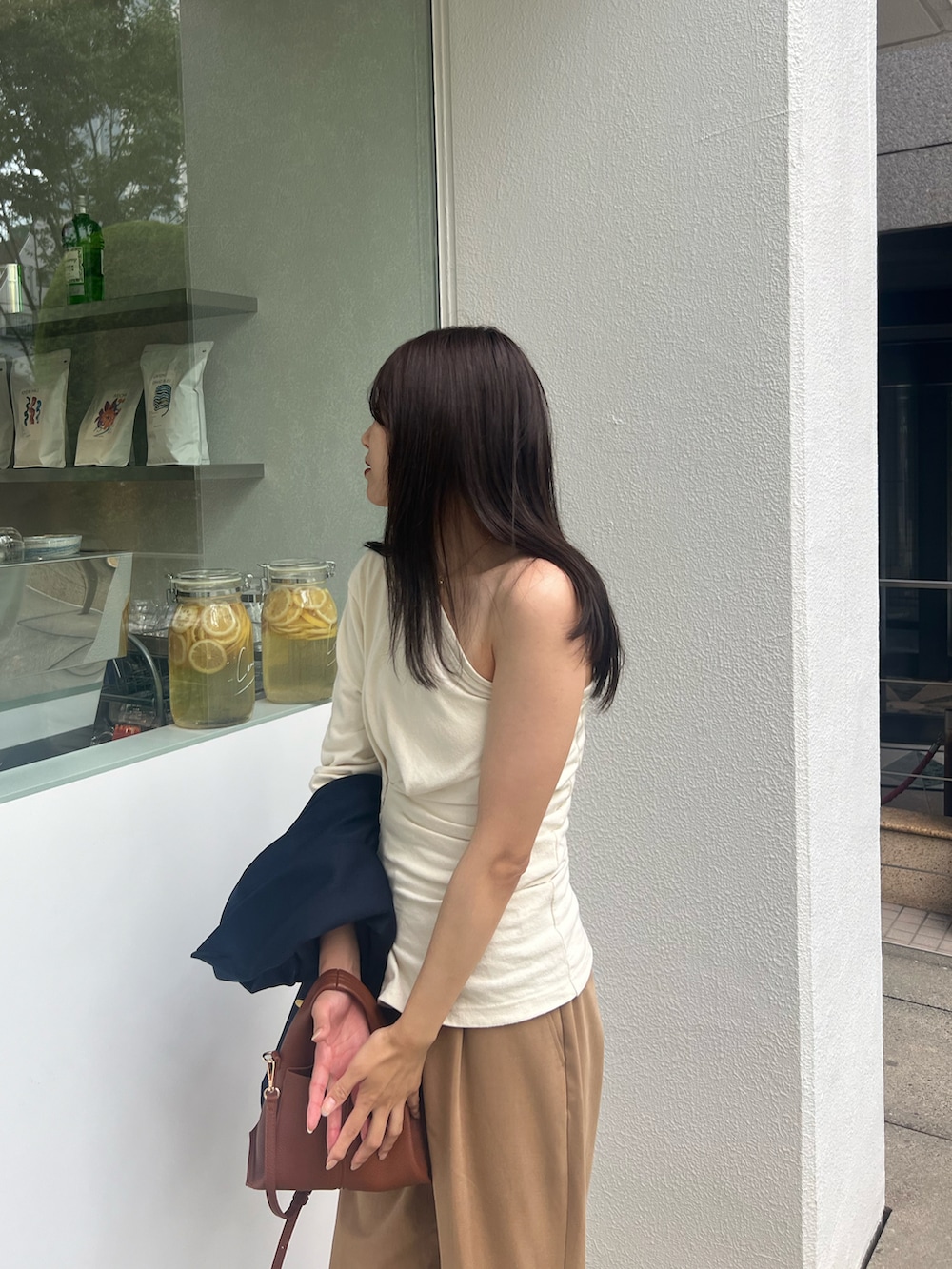 ベージュ系のサンダル、ブラウン系のショルダーバッグ、ベージュ系のトップスを着用したレディースの夏コーディネートの2枚目の写真