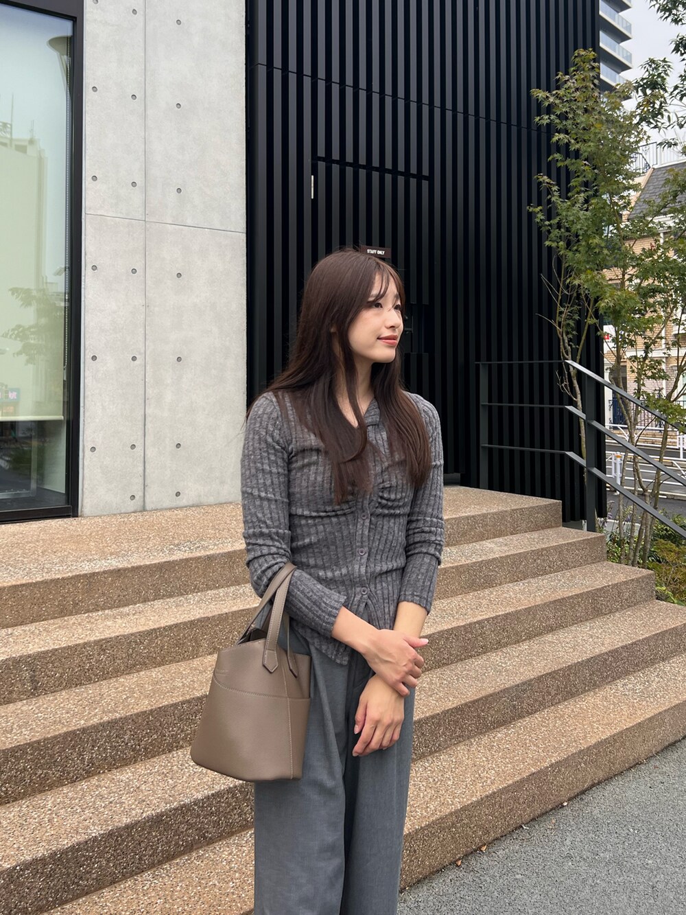 グレー系のトップス、グレー系のパンツ、グレー系のハンドバッグを着用したレディースの秋コーディネートの2枚目の写真