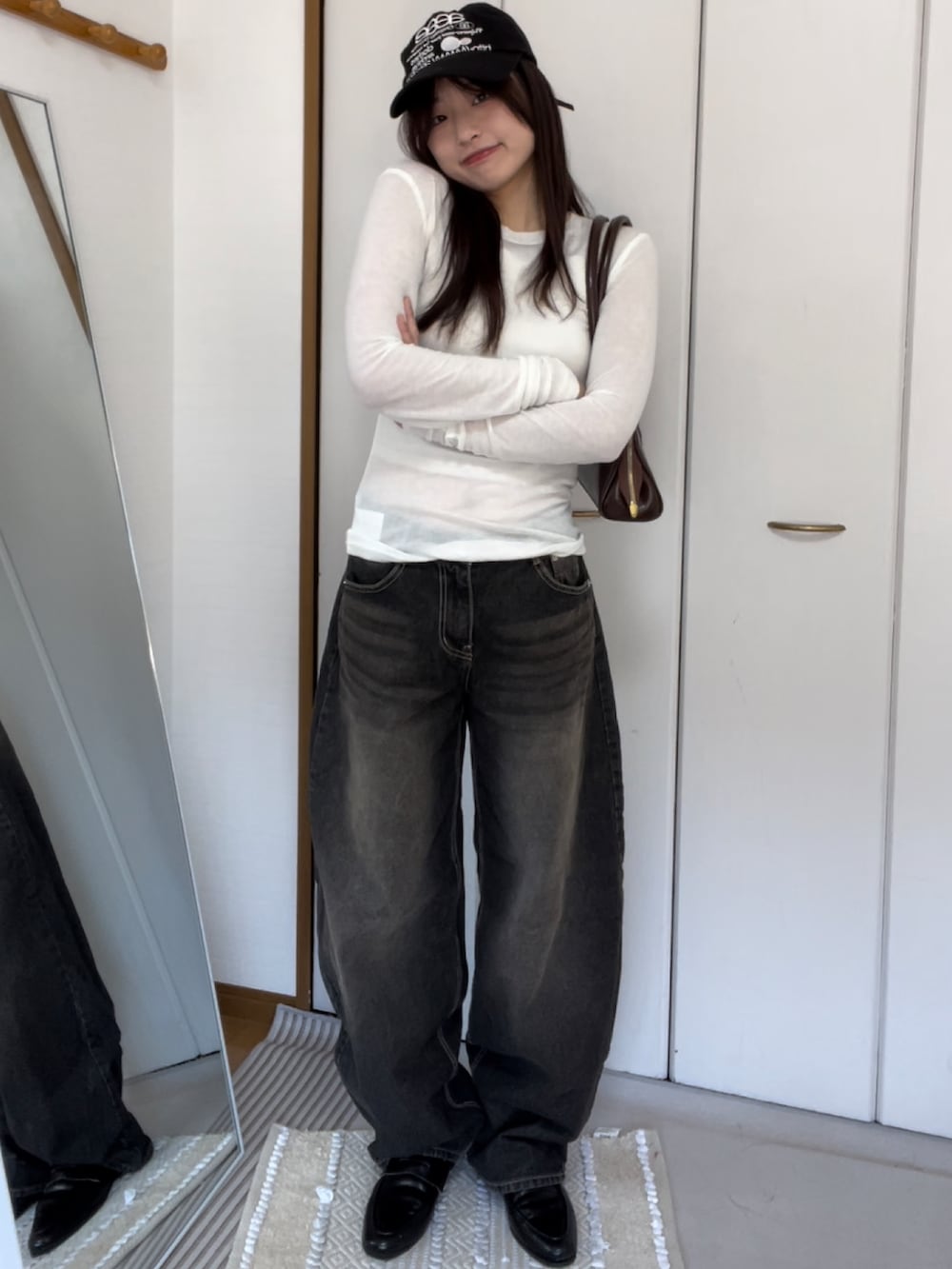 ブラック系のデニムパンツ、ホワイト系のトップス、ブラック系のキャップを着用したレディースの春コーディネートの2枚目の写真