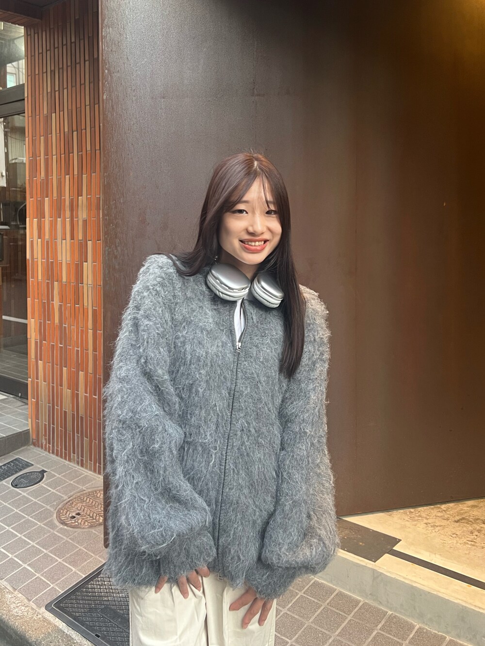 グレー系のカーディガン/ボレロ、ホワイト系のパンツを着用したレディースの秋コーディネートの2枚目の写真