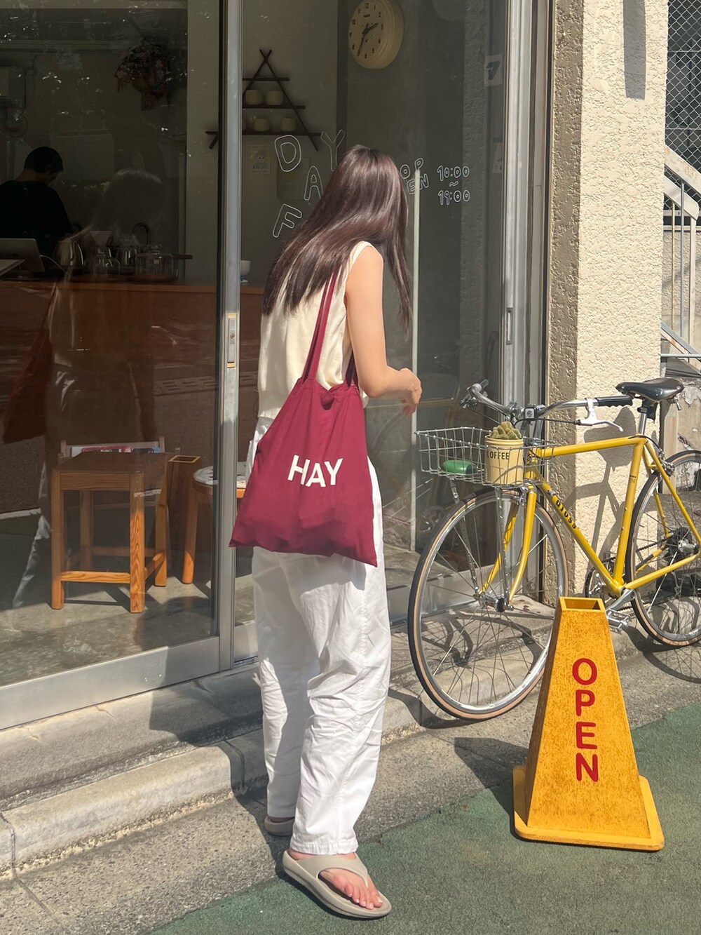 ベージュ系のサンダル、レッド系のトートバッグ、ベージュ系のベストを着用したレディースの夏コーディネートの2枚目の写真