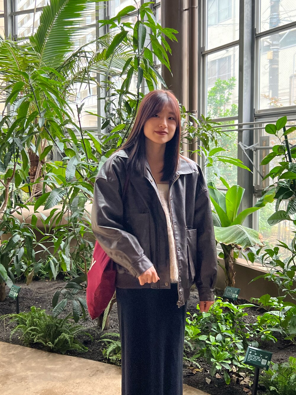 ブラウン系のブルゾン、ブラック系のスカート、レッド系のトートバッグを着用したレディースの秋コーディネートの2枚目の写真