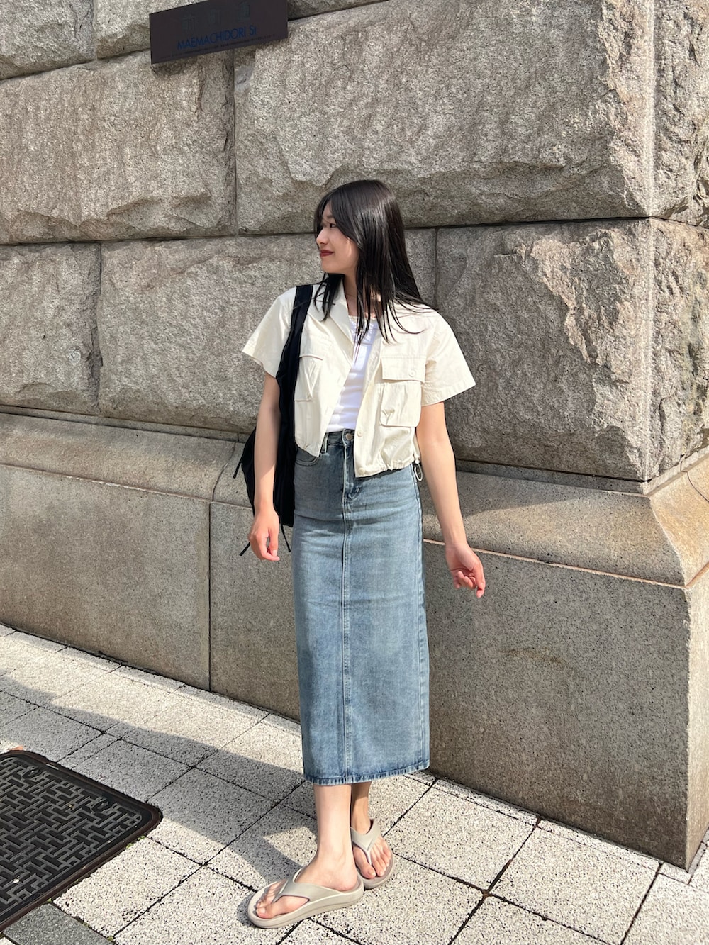 ブルー系のデニムスカート、ブラック系のショルダーバッグ、ベージュ系のサンダルを着用したレディースの春コーディネートの2枚目の写真