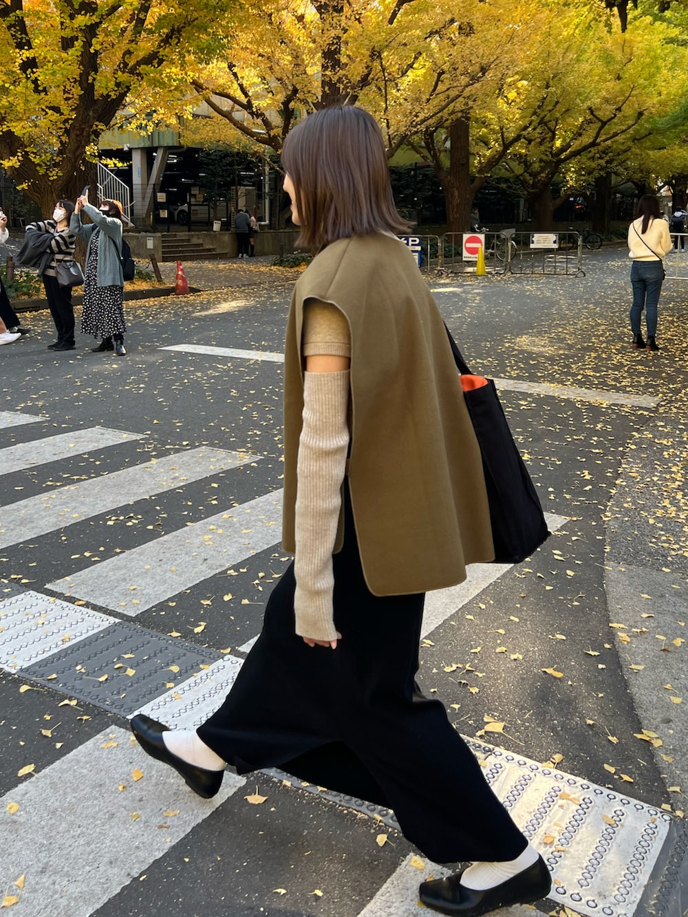 グリーン系のベスト、ブラック系のスカートを着用したレディースの秋コーディネートの3枚目の写真