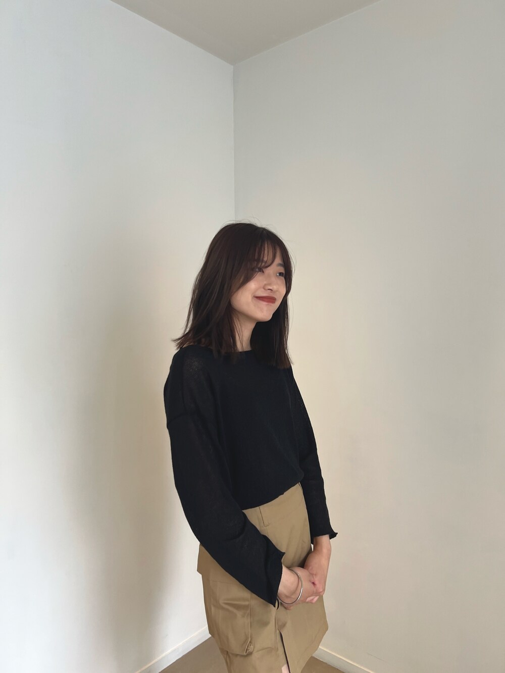 ブラック系のニット/セーター、ベージュ系のスカート、ホワイト系のスニーカーを着用したレディースの夏コーディネートの2枚目の写真