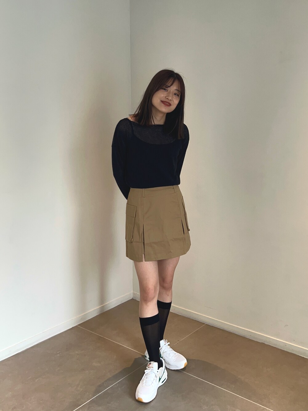 ブラック系のニット/セーター、ベージュ系のスカート、ホワイト系のスニーカーを着用したレディースの夏コーディネートの3枚目の写真