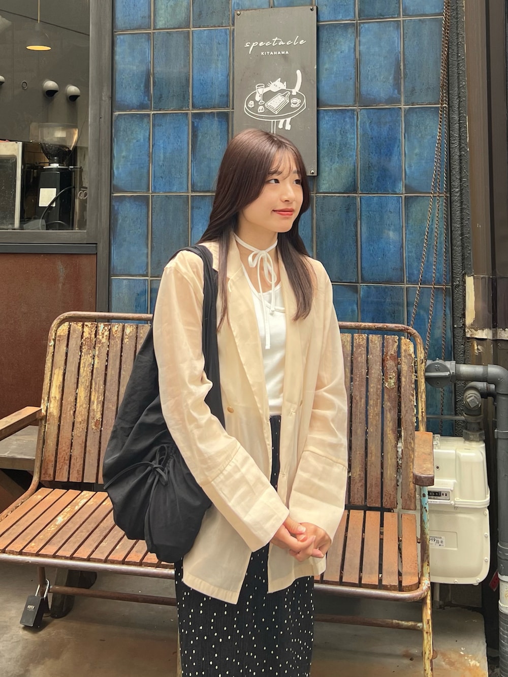 ホワイト系のタンクトップ、ホワイト系のテーラードジャケット、ブラック系のスカートを着用したレディースの春コーディネートの2枚目の写真