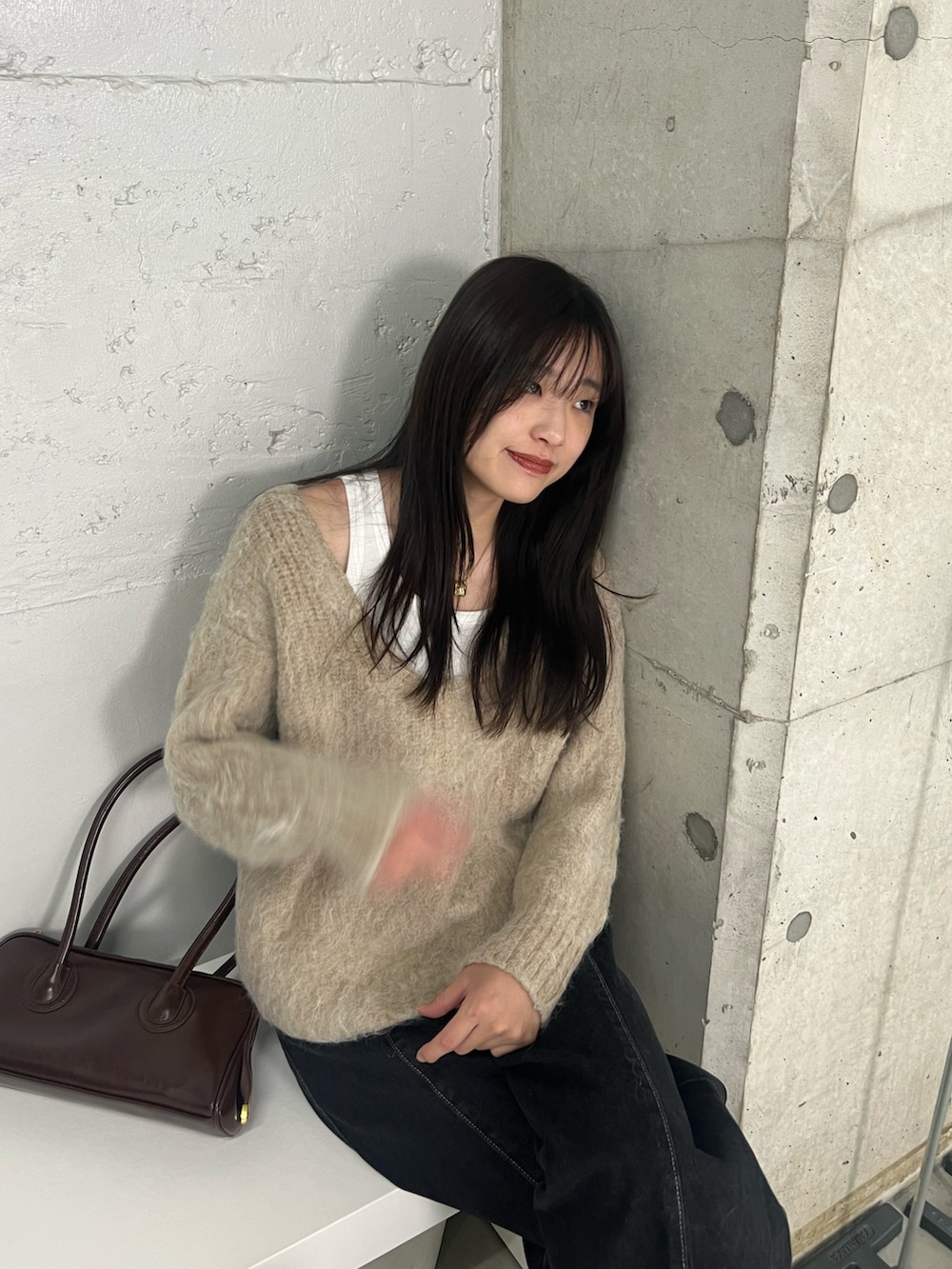 ブラック系のデニムパンツ、ブラウン系のショルダーバッグ、ベージュ系のニット/セーターを着用したレディースの冬コーディネートの2枚目の写真