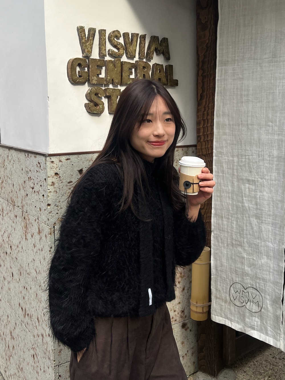 ブラウン系のスラックス、ブラック系のニット/セーター、ブラック系のマフラーを着用したレディースの冬コーディネートの2枚目の写真