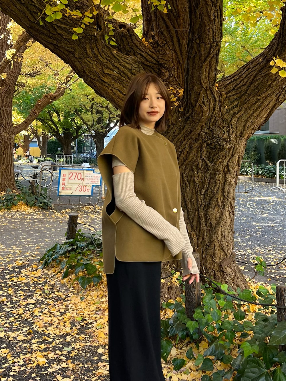 グリーン系のベスト、ブラック系のスカートを着用したレディースの秋コーディネートの2枚目の写真