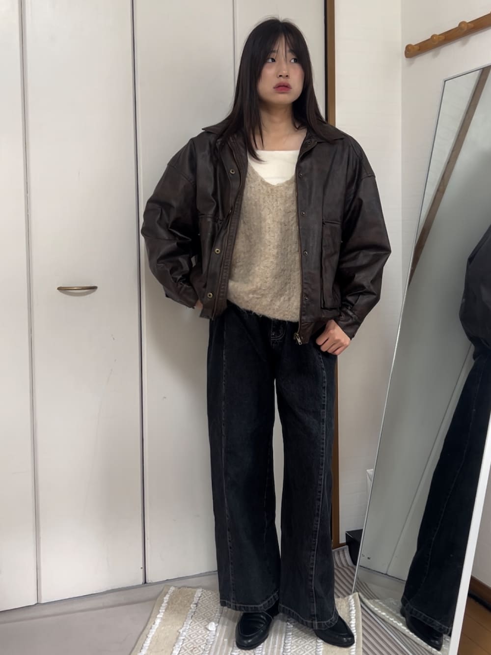 ブラウン系のブルゾン、ベージュ系のニット/セーター、ブラック系のデニムパンツを着用したレディースの秋コーディネートの2枚目の写真