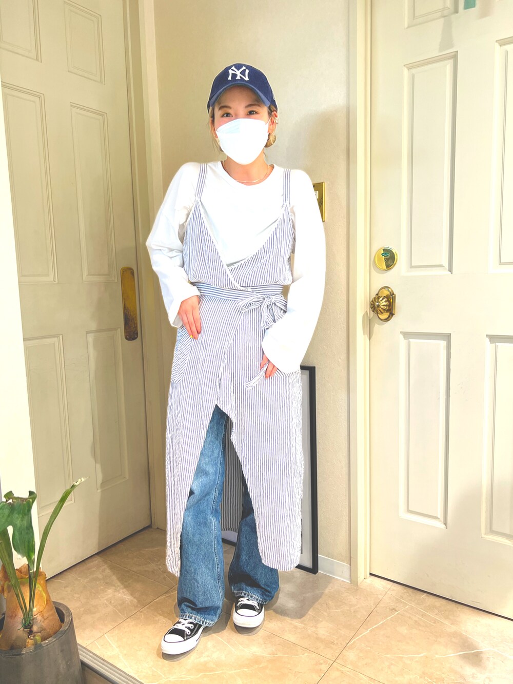 ブルー系のキャミソール、ブルー系のデニムパンツ、ブラック系のスニーカーを着用したレディースの春コーディネートの2枚目の写真