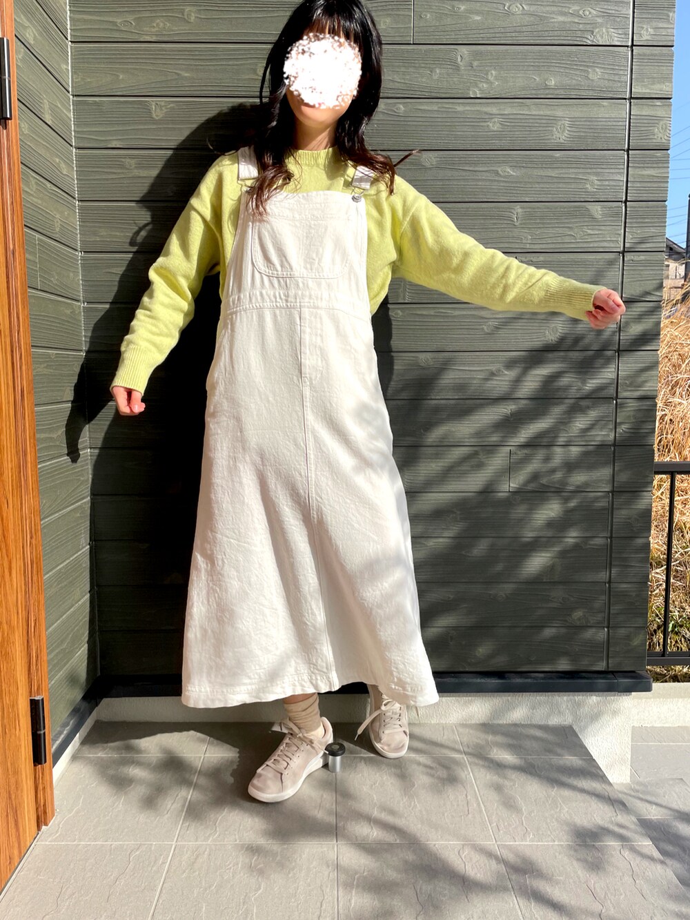 ホワイト系のサロペット/オーバーオール、イエロー系のニット/セーター、ベージュ系のスニーカーを着用したレディースの春コーディネートの2枚目の写真