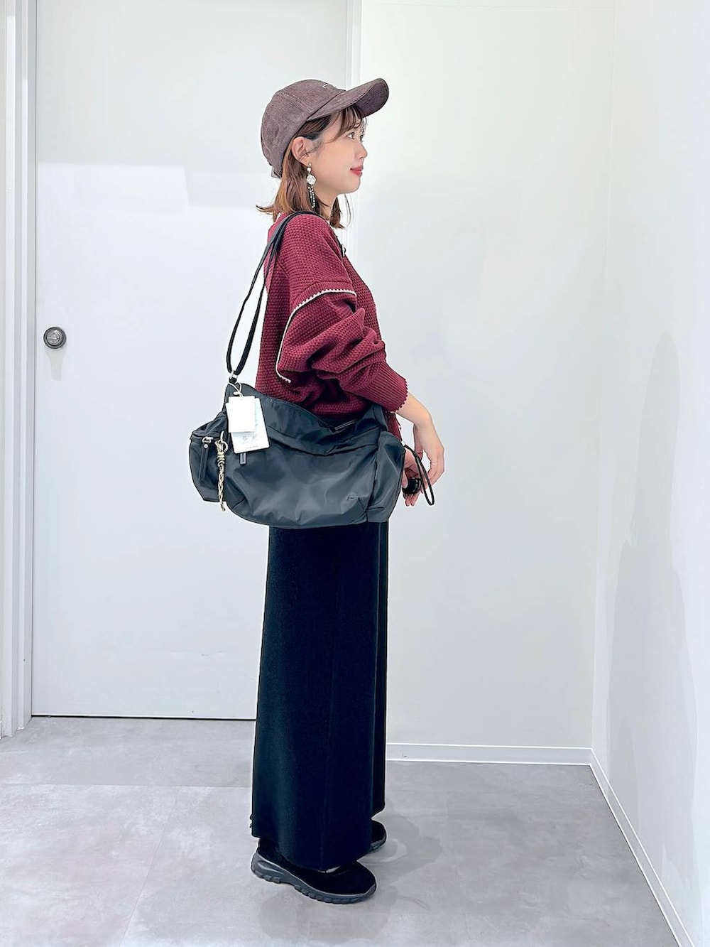 ブラック系のスニーカー、ブラック系のショルダーバッグ、レッド系のカーディガン/ボレロを着用したレディースの秋コーディネートの2枚目の写真