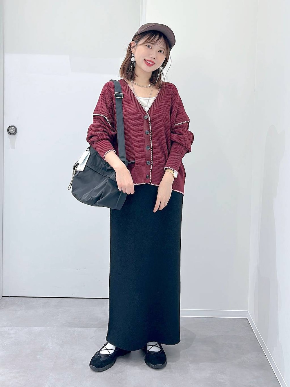 ブラック系のスニーカー、ブラック系のショルダーバッグ、レッド系のカーディガン/ボレロを着用したレディースの秋コーディネートの4枚目の写真