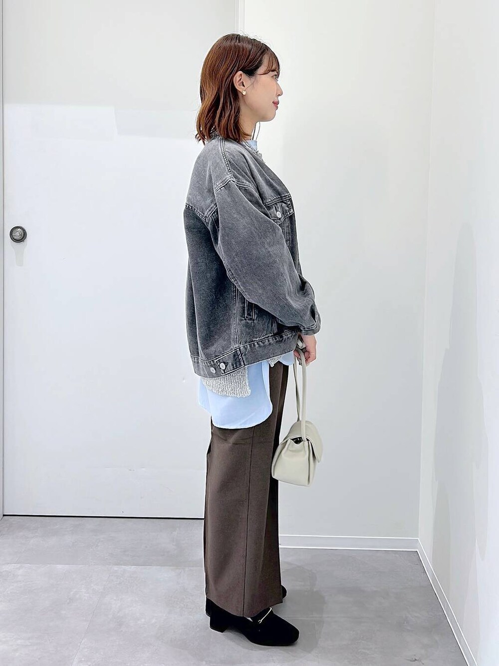 ブラック系のローファー、ブラウン系のスラックス、グレー系のデニムジャケットを着用したレディースの秋コーディネートの2枚目の写真