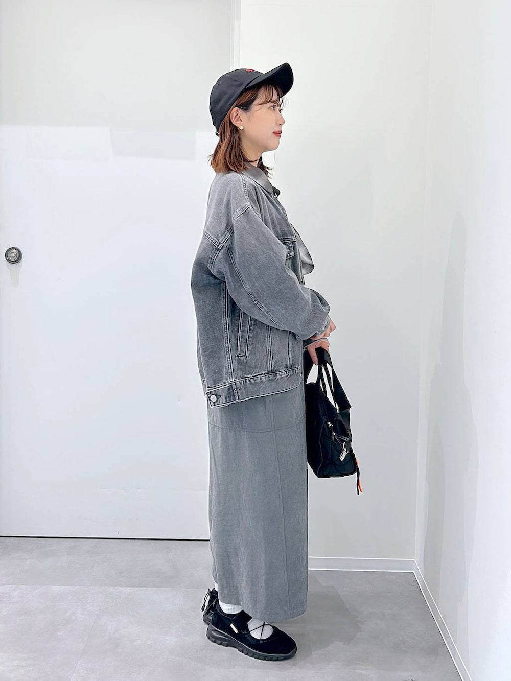 ブラック系のスニーカー、グレー系のデニムジャケット、ブラック系のボストンバッグを着用したレディースの秋コーディネートの2枚目の写真