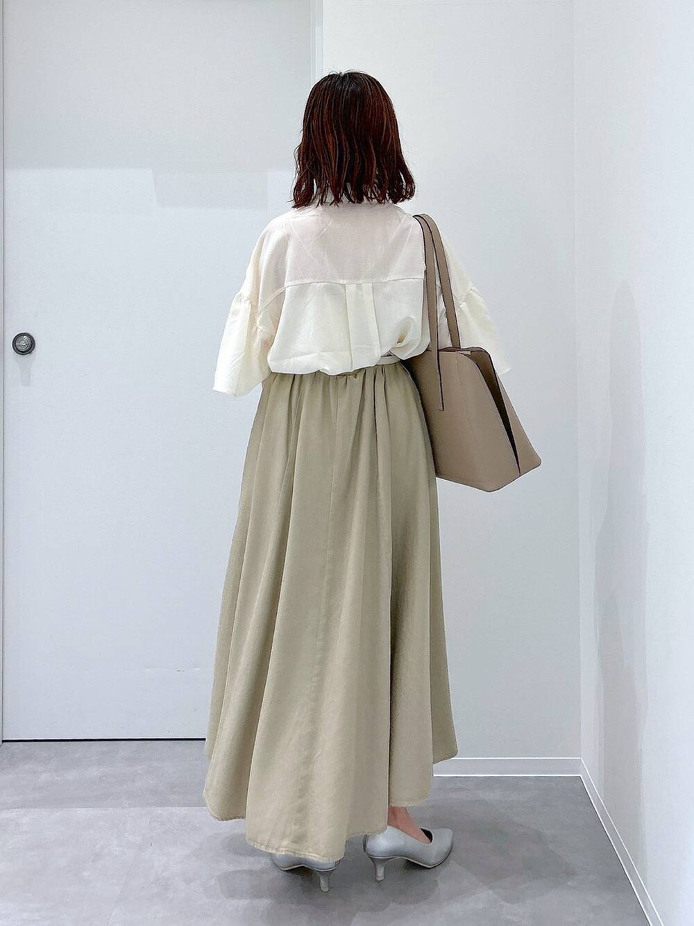 ベージュ系のトートバッグ、シルバー系のパンプス、ベージュ系のスカートを着用したレディースの夏コーディネートの3枚目の写真
