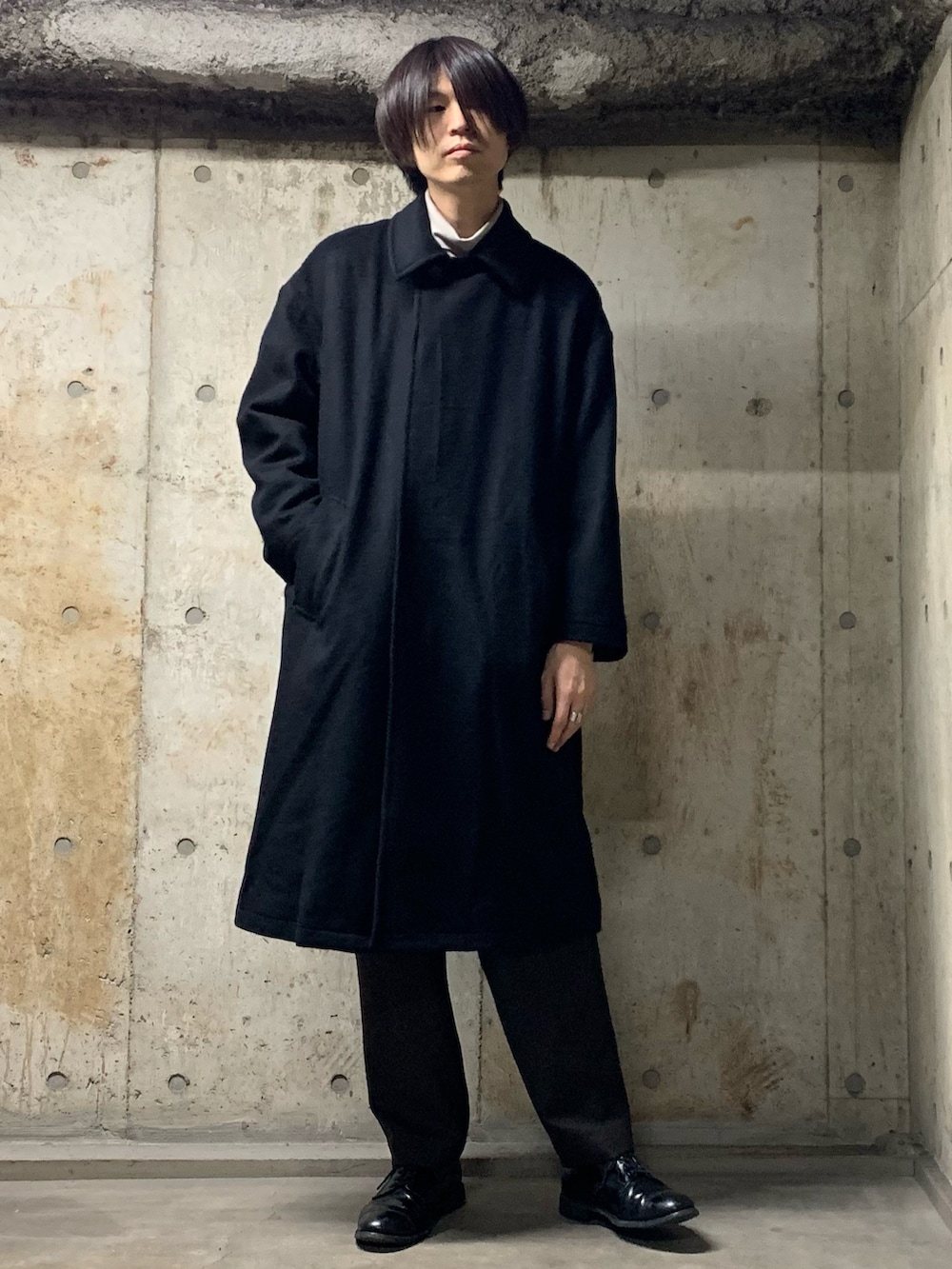 ブラック系のステンカラーコート、グレー系のTシャツ/カットソー、ブラック系のその他パンツを着用したメンズの秋コーディネートの4枚目の写真