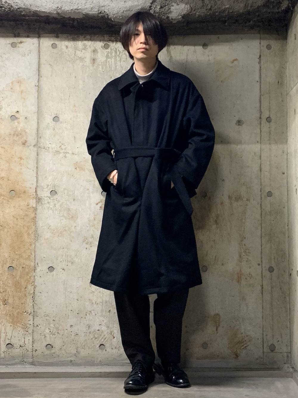 ブラック系のステンカラーコート、グレー系のTシャツ/カットソー、ブラック系のその他パンツを着用したメンズの秋コーディネートの3枚目の写真