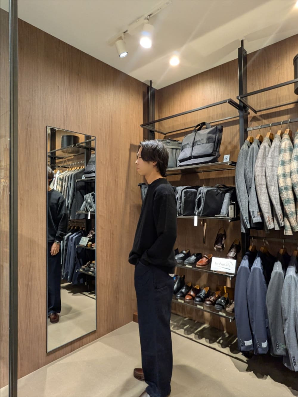 ブラック系のニット/セーター、ブルー系のデニムパンツ、グレー系のショルダーバッグを着用したメンズの秋コーディネートの3枚目の写真