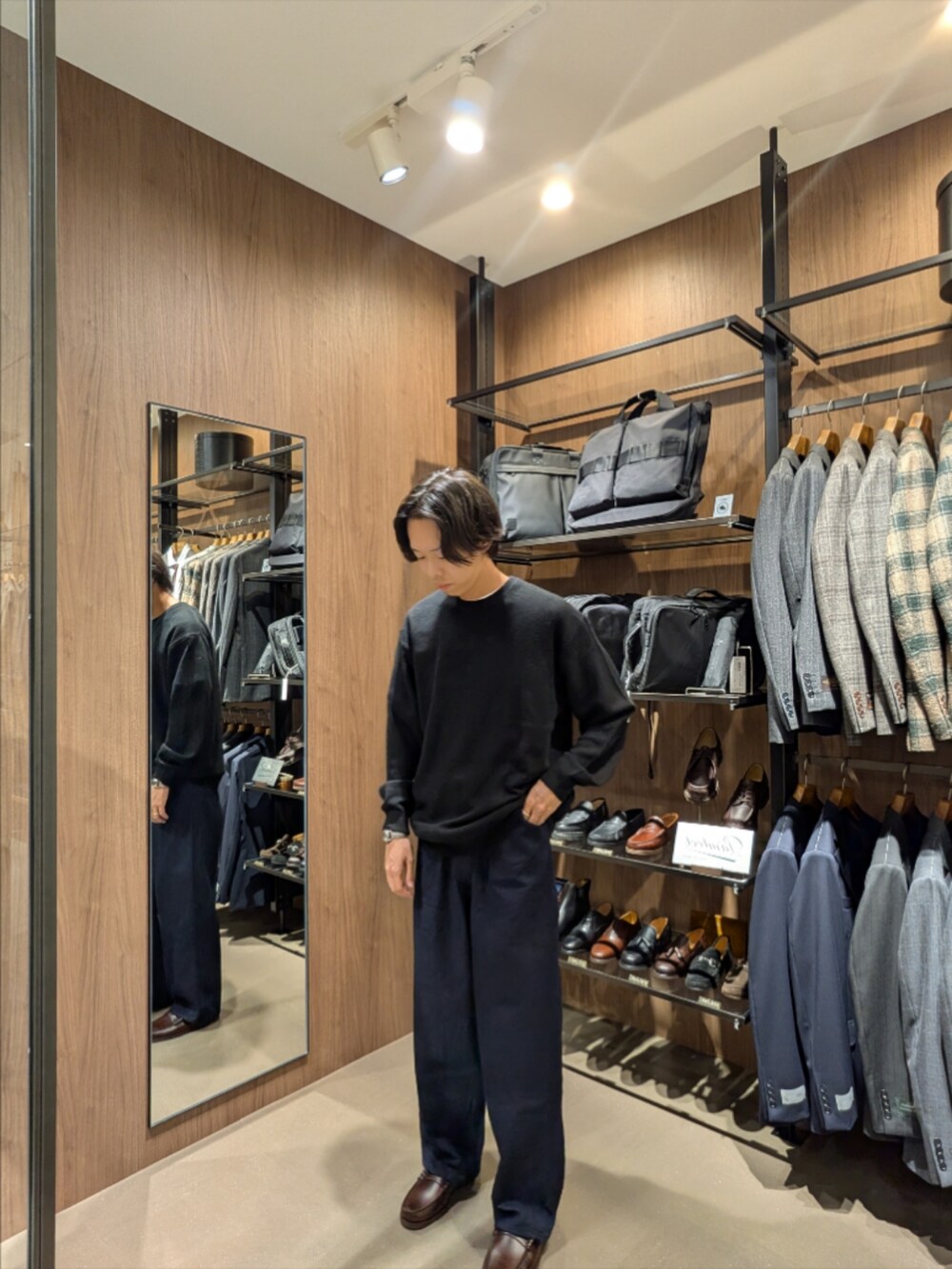 ブラック系のニット/セーター、ブルー系のデニムパンツ、グレー系のショルダーバッグを着用したメンズの秋コーディネートの2枚目の写真