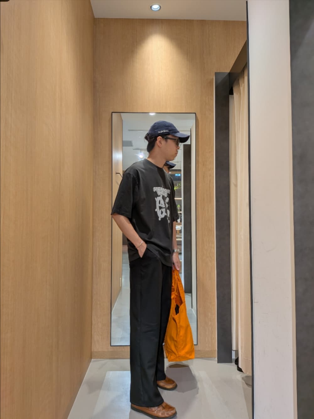 グレー系のTシャツ/カットソー、オレンジ系のトートバッグ、ブラック系のサングラスを着用したメンズの夏コーディネートの2枚目の写真