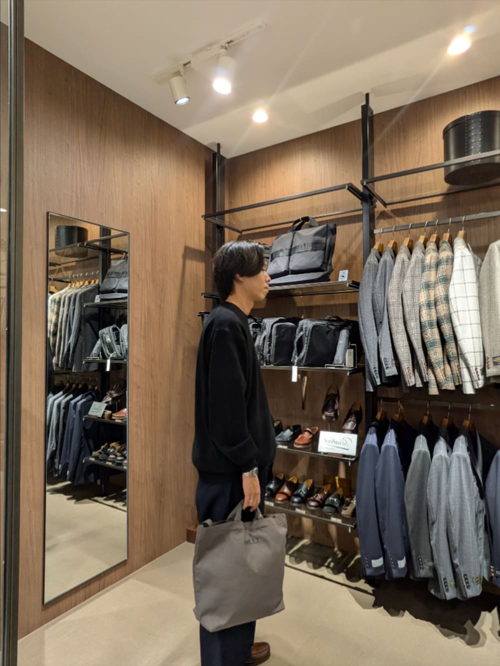 ブラック系のニット/セーター、ブルー系のデニムパンツ、グレー系のショルダーバッグを着用したメンズの秋コーディネートの4枚目の写真