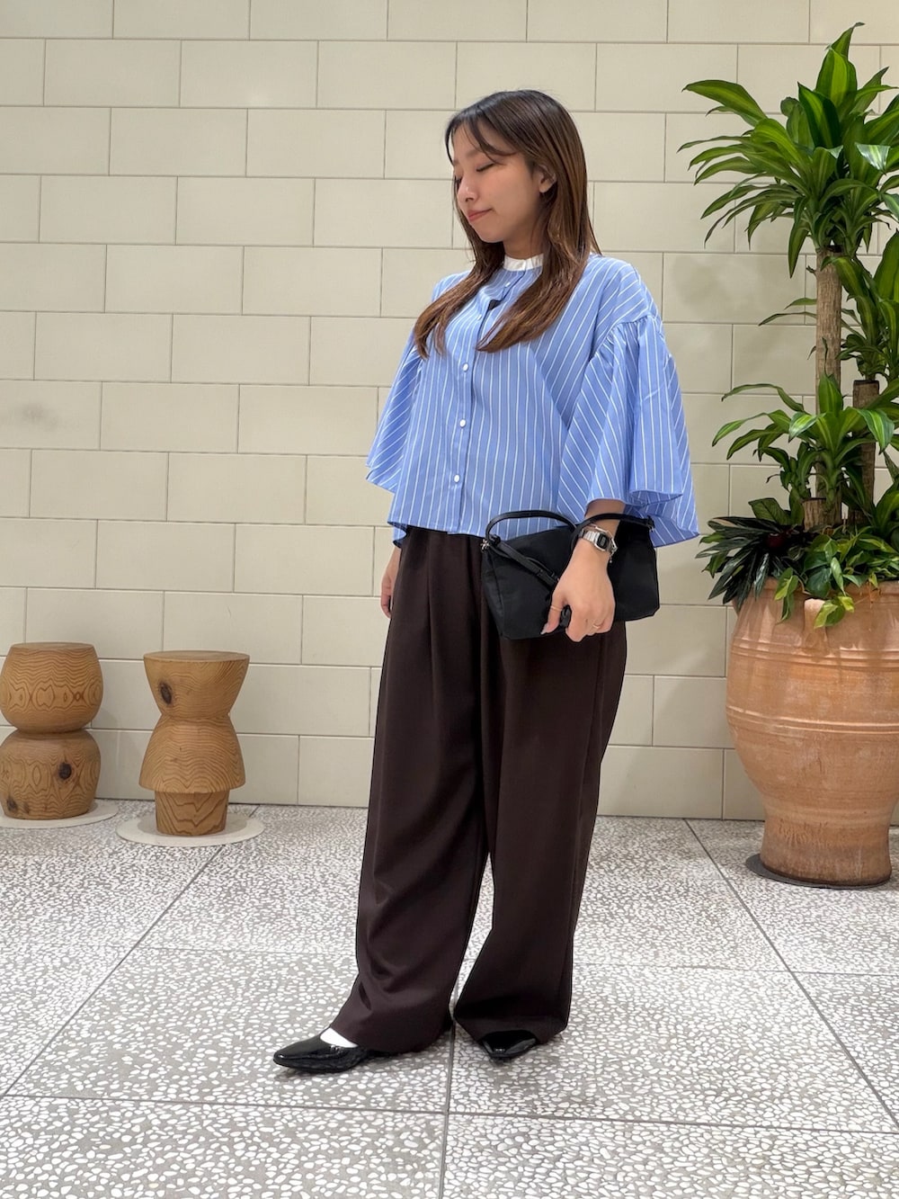 ブルー系のシャツ/ブラウス、ブラウン系のその他パンツ、ブラック系のショルダーバッグを着用したレディースの春コーディネートの2枚目の写真