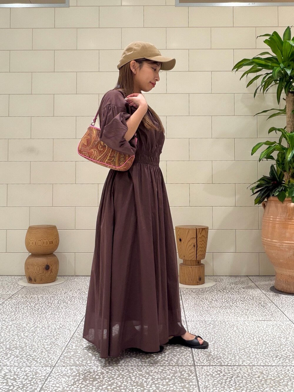 オレンジ系のハンドバッグ、ブラウン系のワンピース、ブラック系のサンダルを着用したレディースの春コーディネートの2枚目の写真