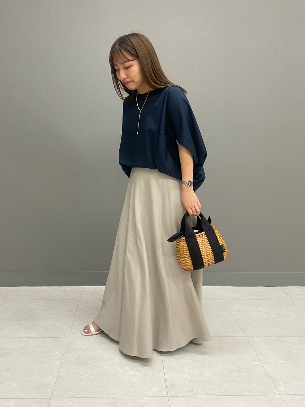 ブルー系のTシャツ/カットソー、ベージュ系のスカート、ブラック系のハンドバッグを着用したレディースの夏コーディネートの3枚目の写真