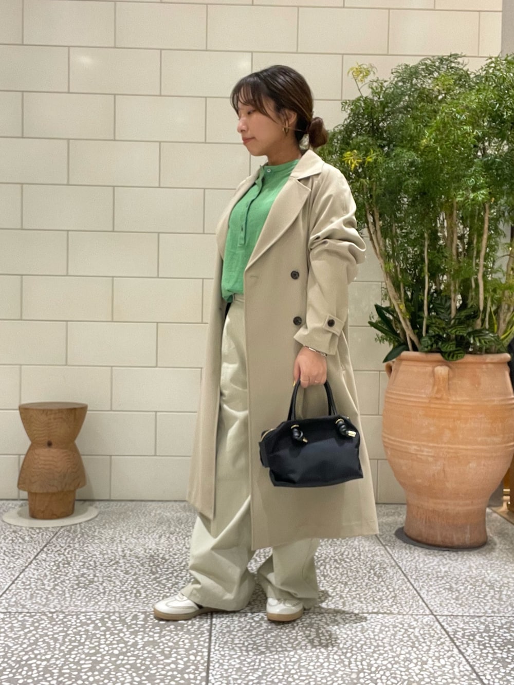 ベージュ系のトレンチコート、グリーン系のニット/セーター、ブラック系のトートバッグを着用したレディースの冬コーディネートの3枚目の写真