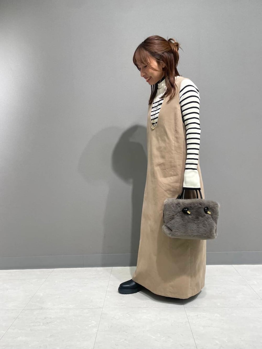 ホワイト系のニット/セーター、ベージュ系のワンピース、ブラック系のブーツを着用したレディースの秋コーディネートの4枚目の写真