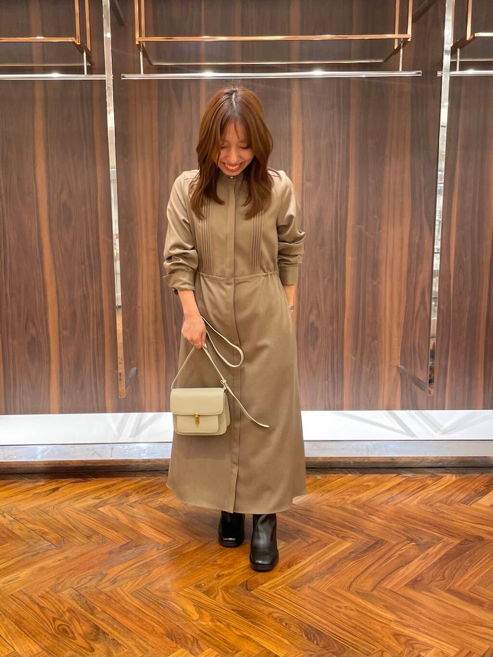 ブラウン系のワンピース、ブラック系のブーツ、ベージュ系のショルダーバッグを着用したレディースの秋コーディネートの3枚目の写真