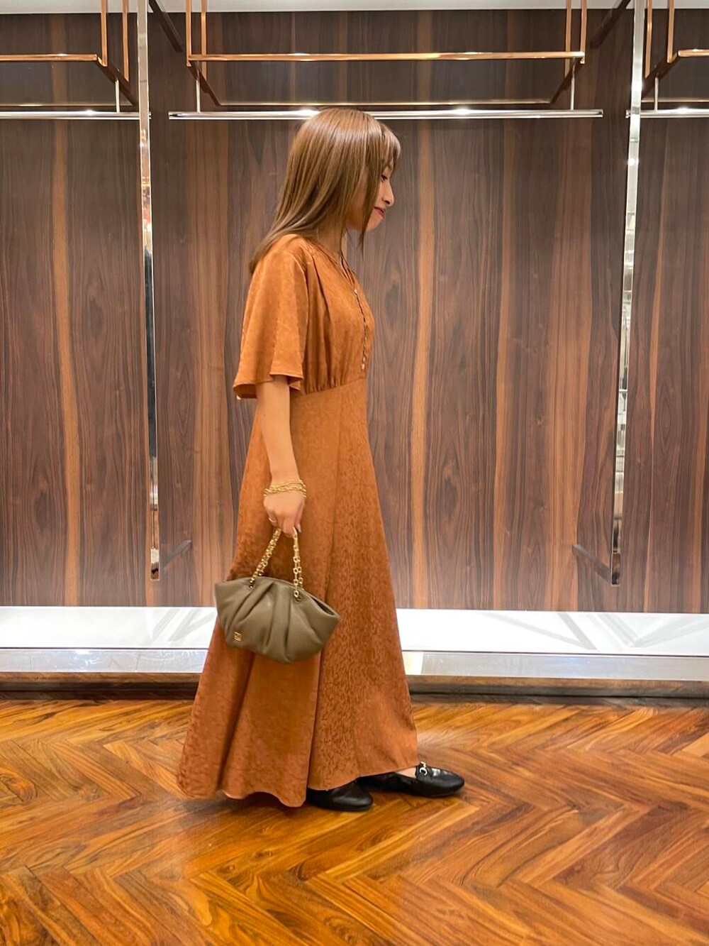 ブラック系のローファー、ブラウン系のハンドバッグ、オレンジ系のワンピースを着用したレディースの秋コーディネートの2枚目の写真