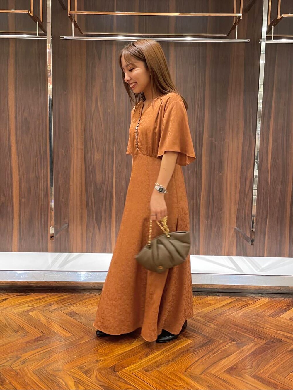 ブラック系のローファー、ブラウン系のハンドバッグ、オレンジ系のワンピースを着用したレディースの秋コーディネートの3枚目の写真