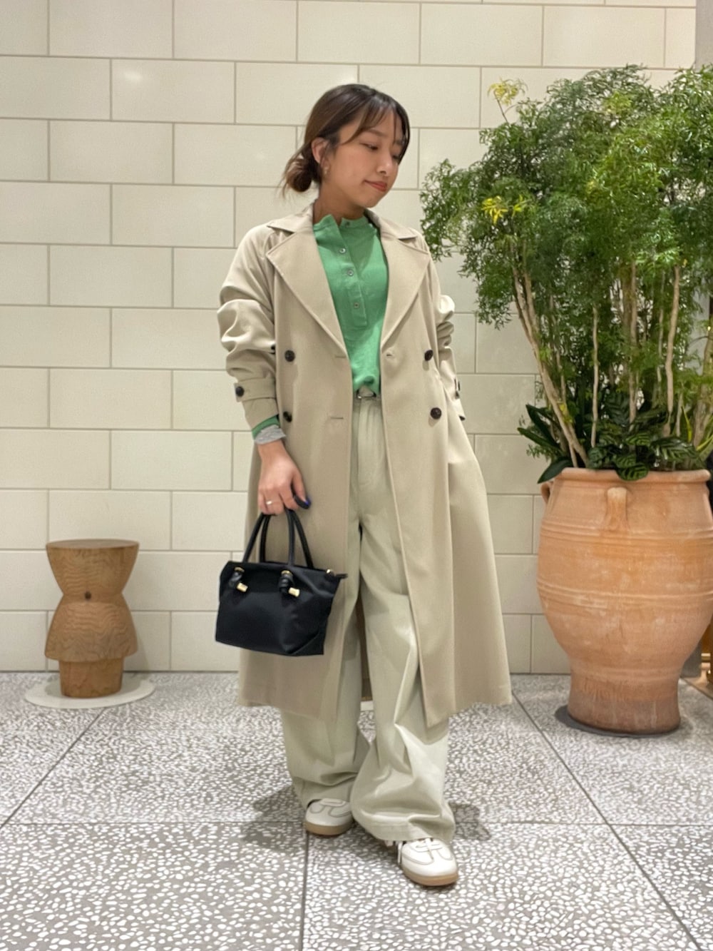 ベージュ系のトレンチコート、グリーン系のニット/セーター、ブラック系のトートバッグを着用したレディースの冬コーディネートの2枚目の写真