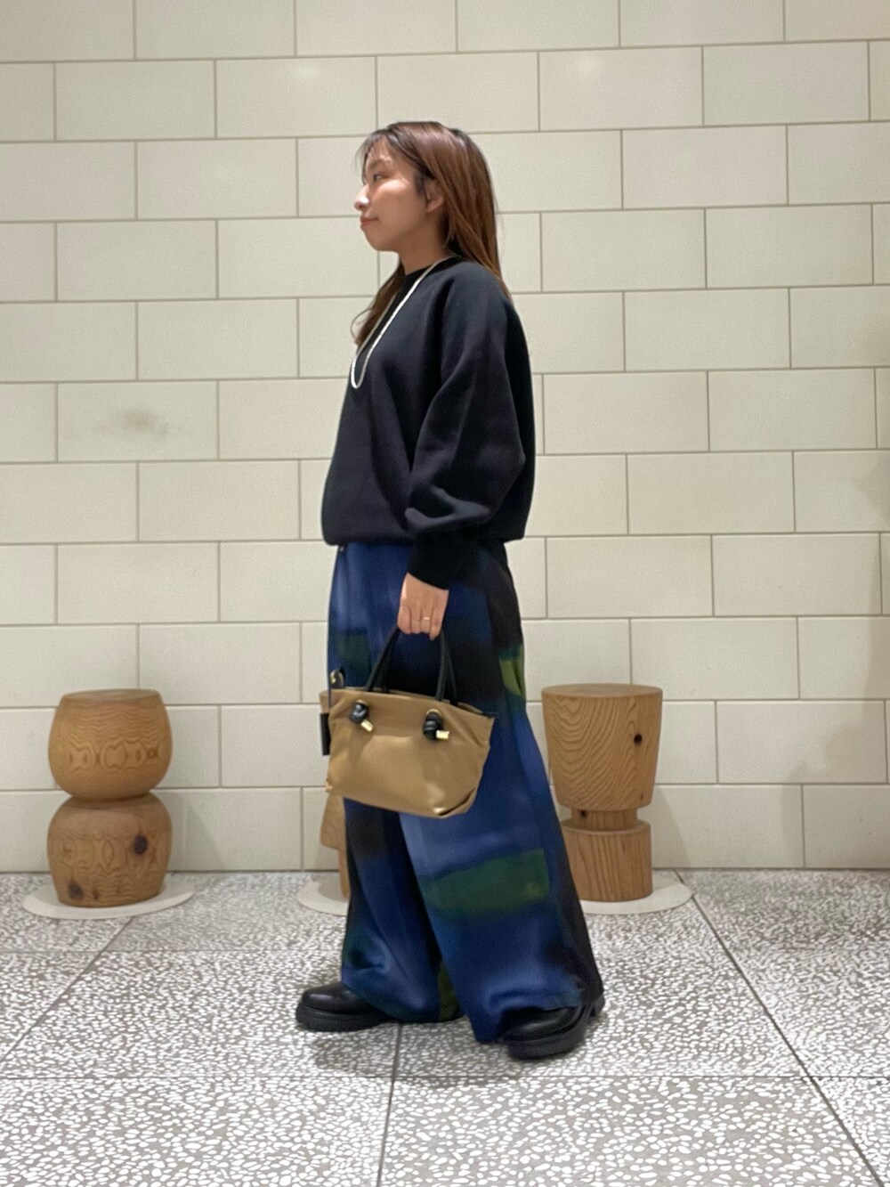 ブラック系のニット/セーター、ベージュ系のトートバッグ、ブルー系のパンツを着用したレディースの秋コーディネートの2枚目の写真