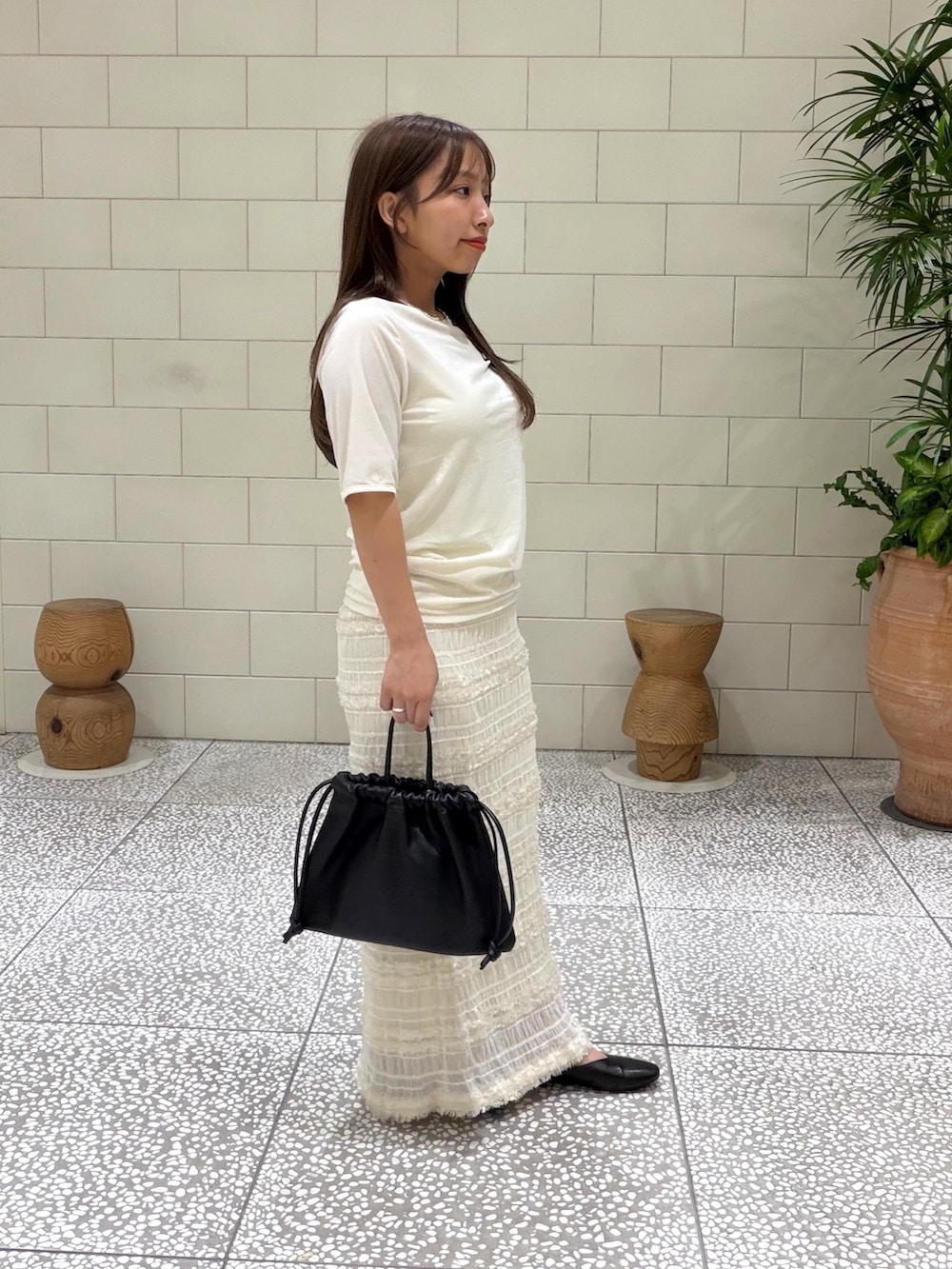 ホワイト系のTシャツ/カットソー、ホワイト系のスカート、ブラック系のバッグを着用したレディースの夏コーディネートの3枚目の写真