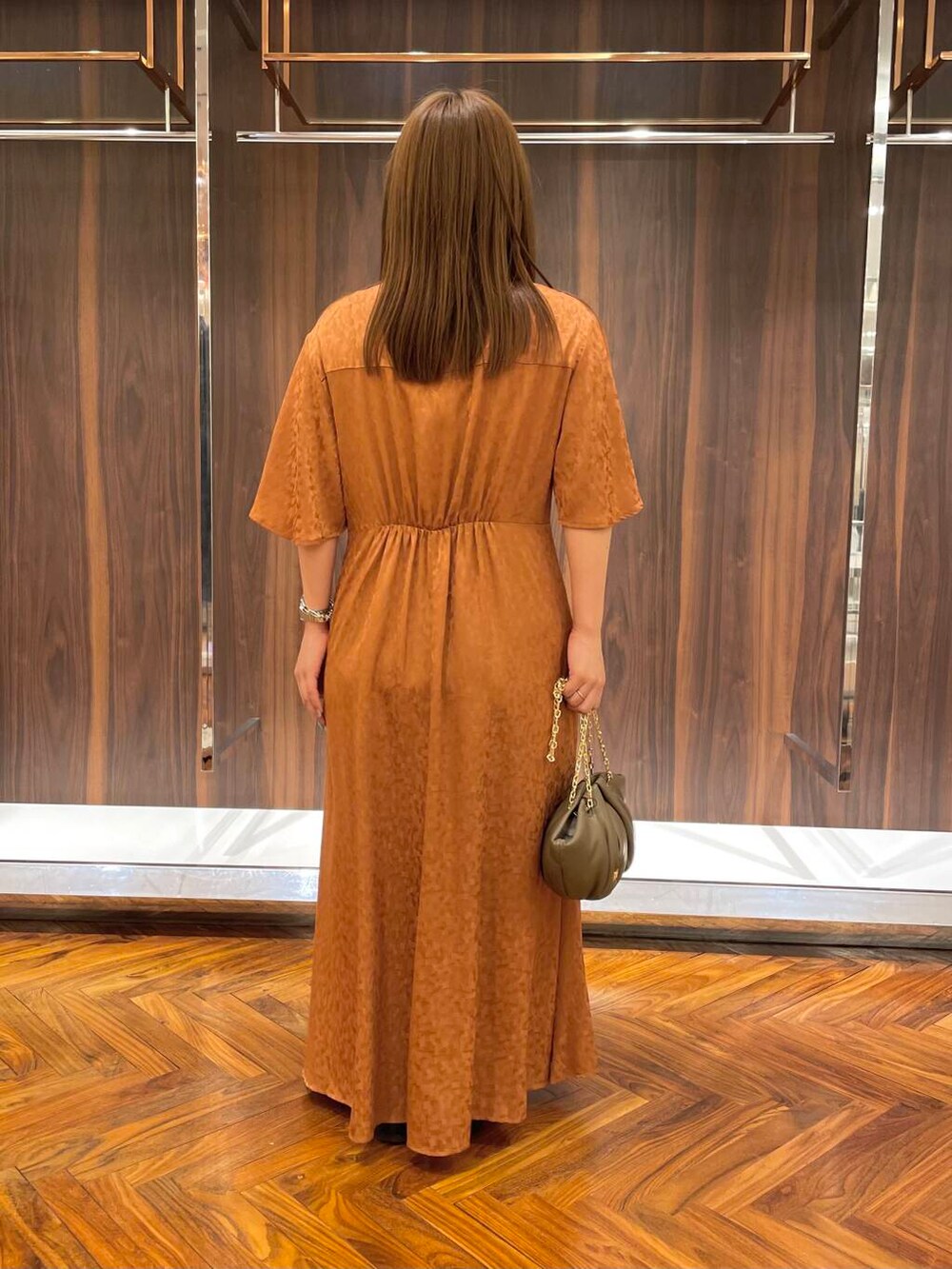 ブラック系のローファー、ブラウン系のハンドバッグ、オレンジ系のワンピースを着用したレディースの秋コーディネートの4枚目の写真