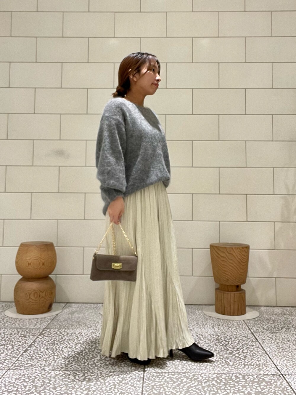 グレー系のニット/セーター、グリーン系のスカート、ブラウン系のショルダーバッグを着用したレディースの秋コーディネートの3枚目の写真