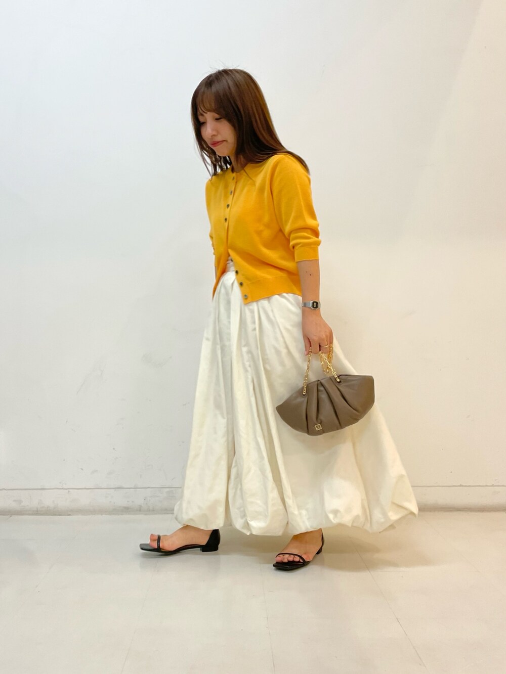 ゴールド系のカーディガン/ボレロ、ホワイト系のスカートを着用したレディースの夏コーディネートの2枚目の写真