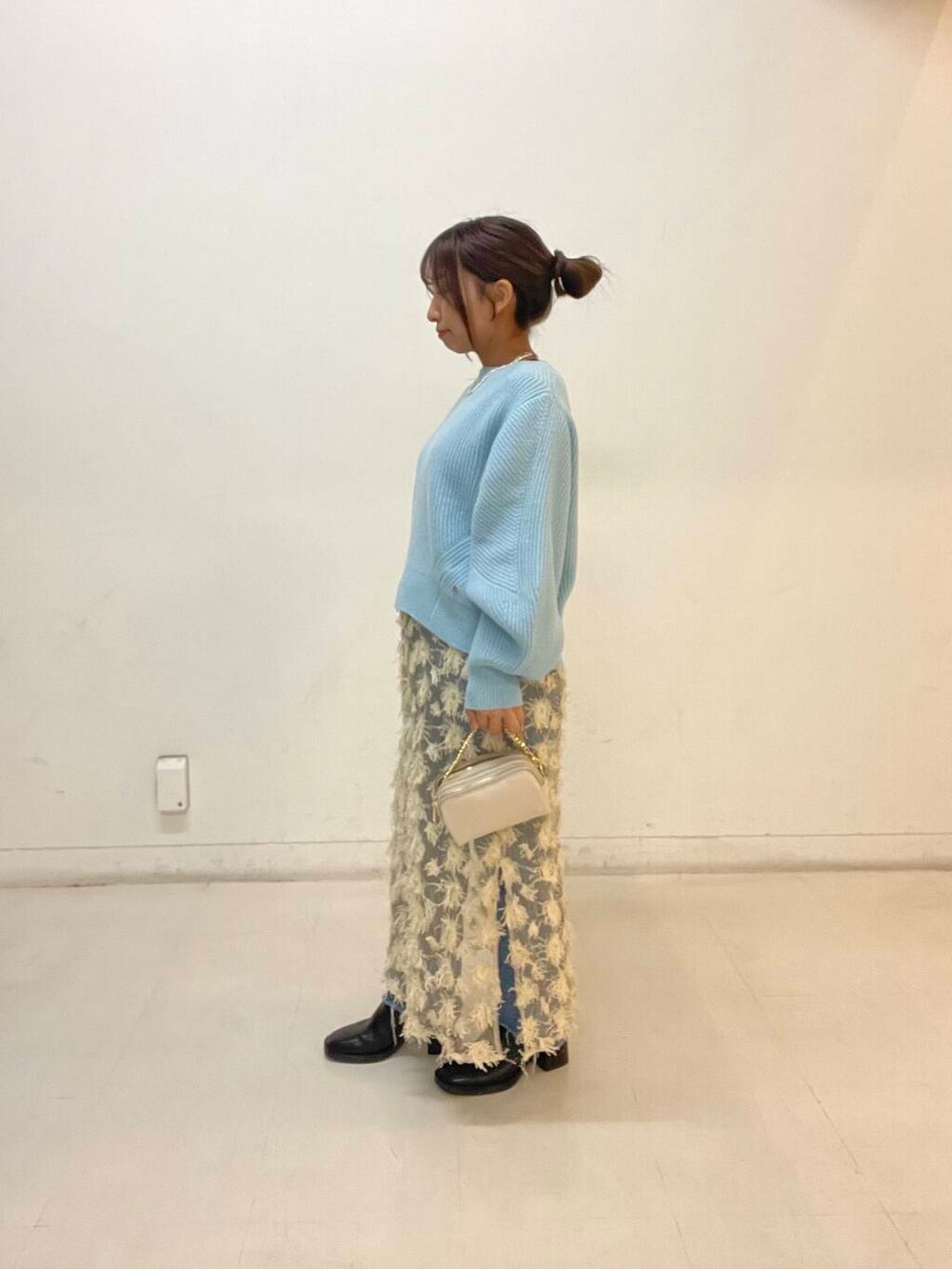 ベージュ系のスカート、ブルー系のニット/セーター、ホワイト系のショルダーバッグを着用したレディースの秋コーディネートの2枚目の写真