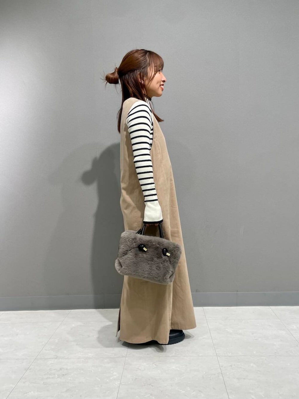 ホワイト系のニット/セーター、ベージュ系のワンピース、ブラック系のブーツを着用したレディースの秋コーディネートの2枚目の写真