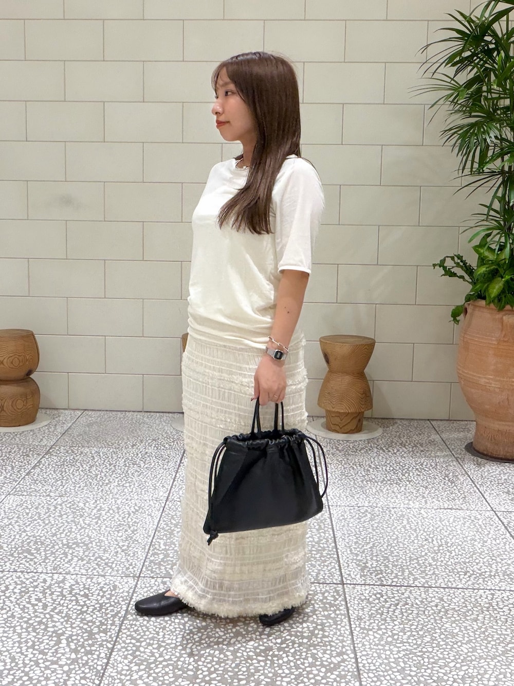 ホワイト系のTシャツ/カットソー、ホワイト系のスカート、ブラック系のバッグを着用したレディースの夏コーディネートの2枚目の写真