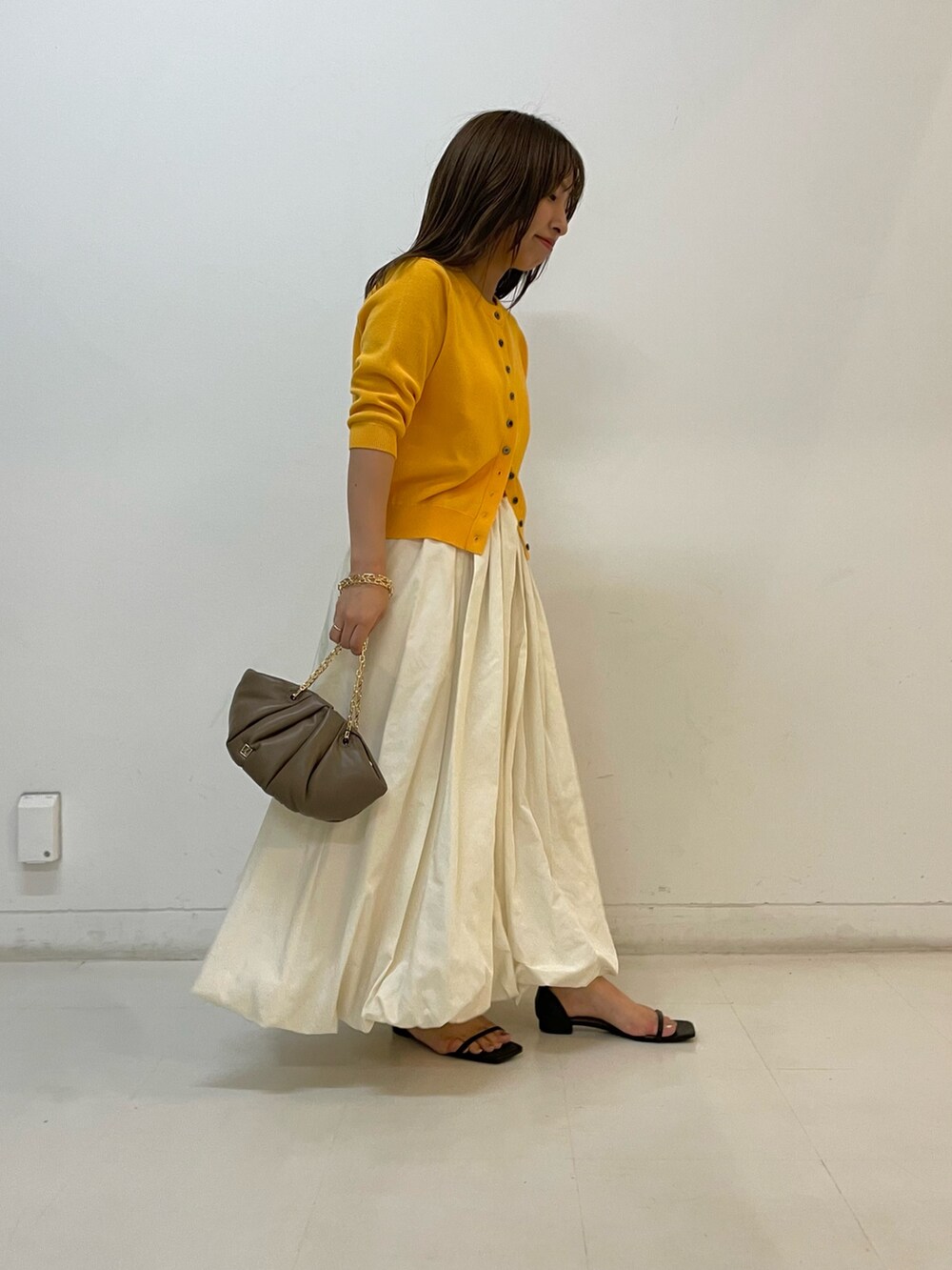 ゴールド系のカーディガン/ボレロ、ホワイト系のスカートを着用したレディースの夏コーディネートの3枚目の写真