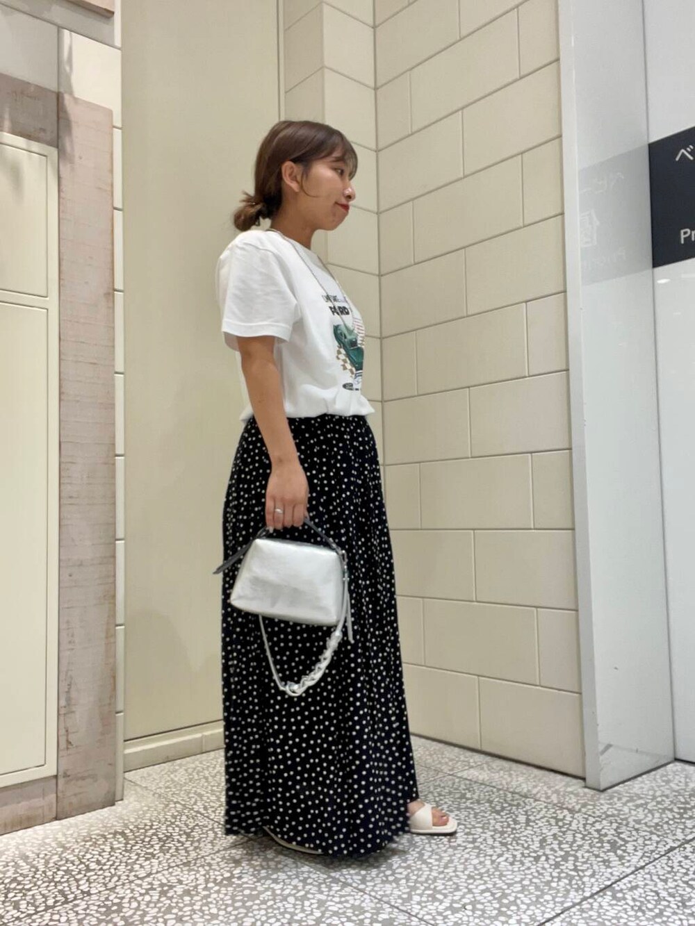 ホワイト系のサンダル、ホワイト系のTシャツ/カットソー、ブラック系のスカートを着用したレディースの夏コーディネートの3枚目の写真