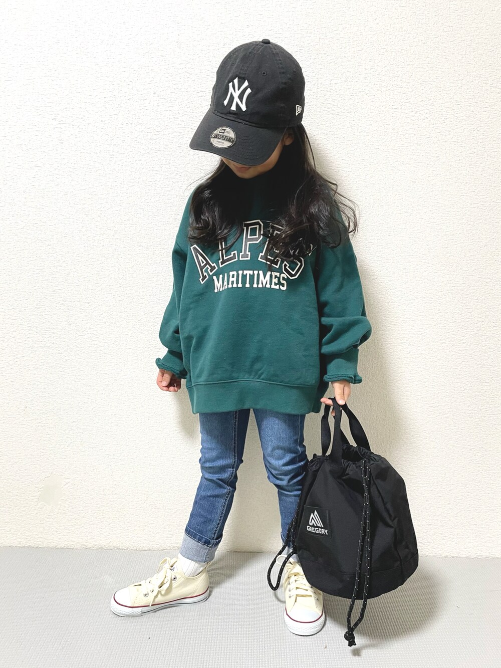 グリーン系のスウェット、ブルー系のデニムパンツ、ホワイト系のスニーカーを着用したキッズの冬コーディネートの3枚目の写真